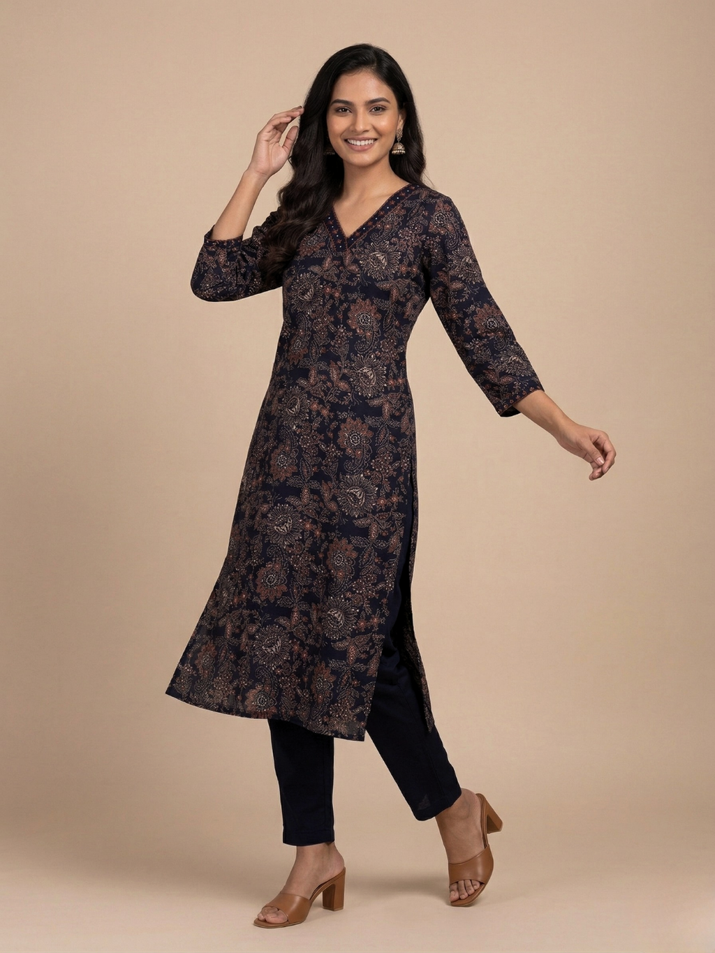 Woman wearing a long dark patterned dress on a beige background