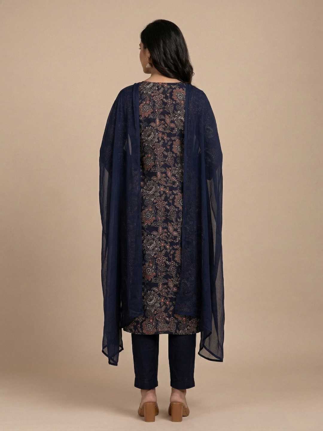 Woman wearing a navy blue floral outfit with a sheer cover-up on a beige background