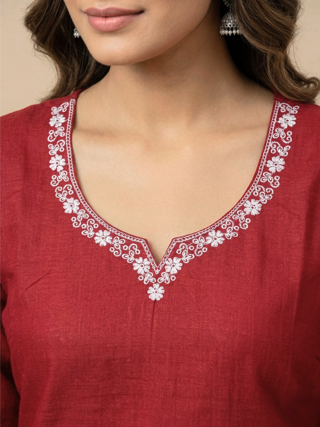 Red kurta with white floral embroidery on a beige background