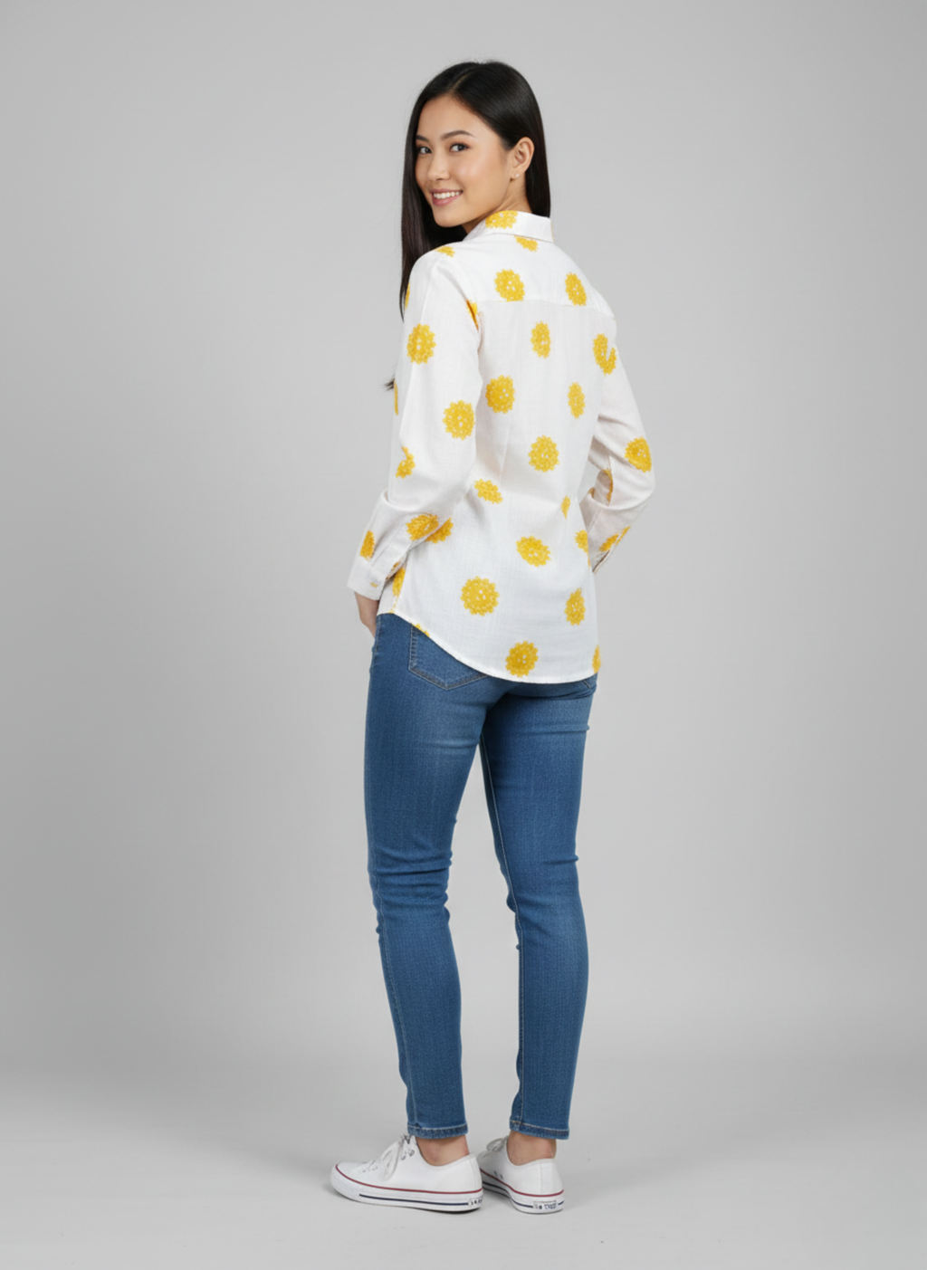 gray parrot shirt Woman wearing a white blouse with yellow polka dots and blue jeans on a gray background