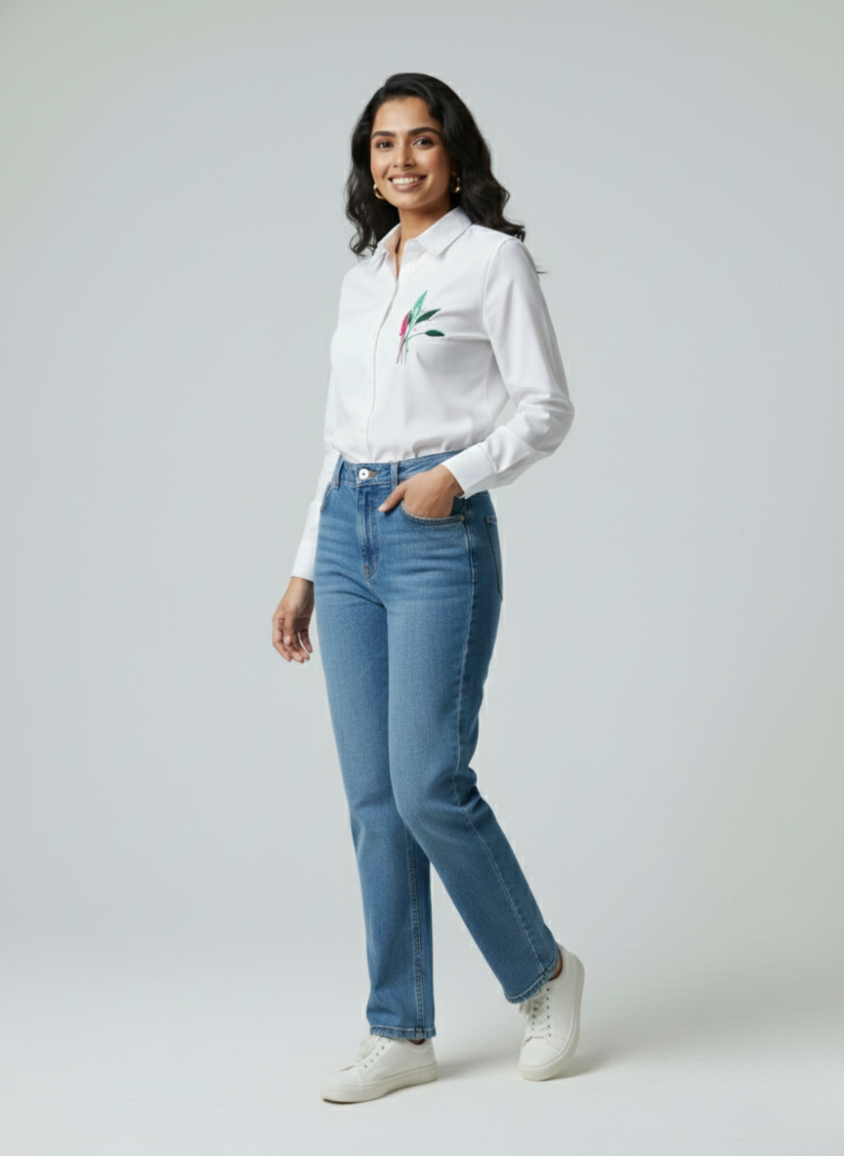 gray parrot shirt Woman wearing a white blouse with floral embroidery and blue jeans on a plain background