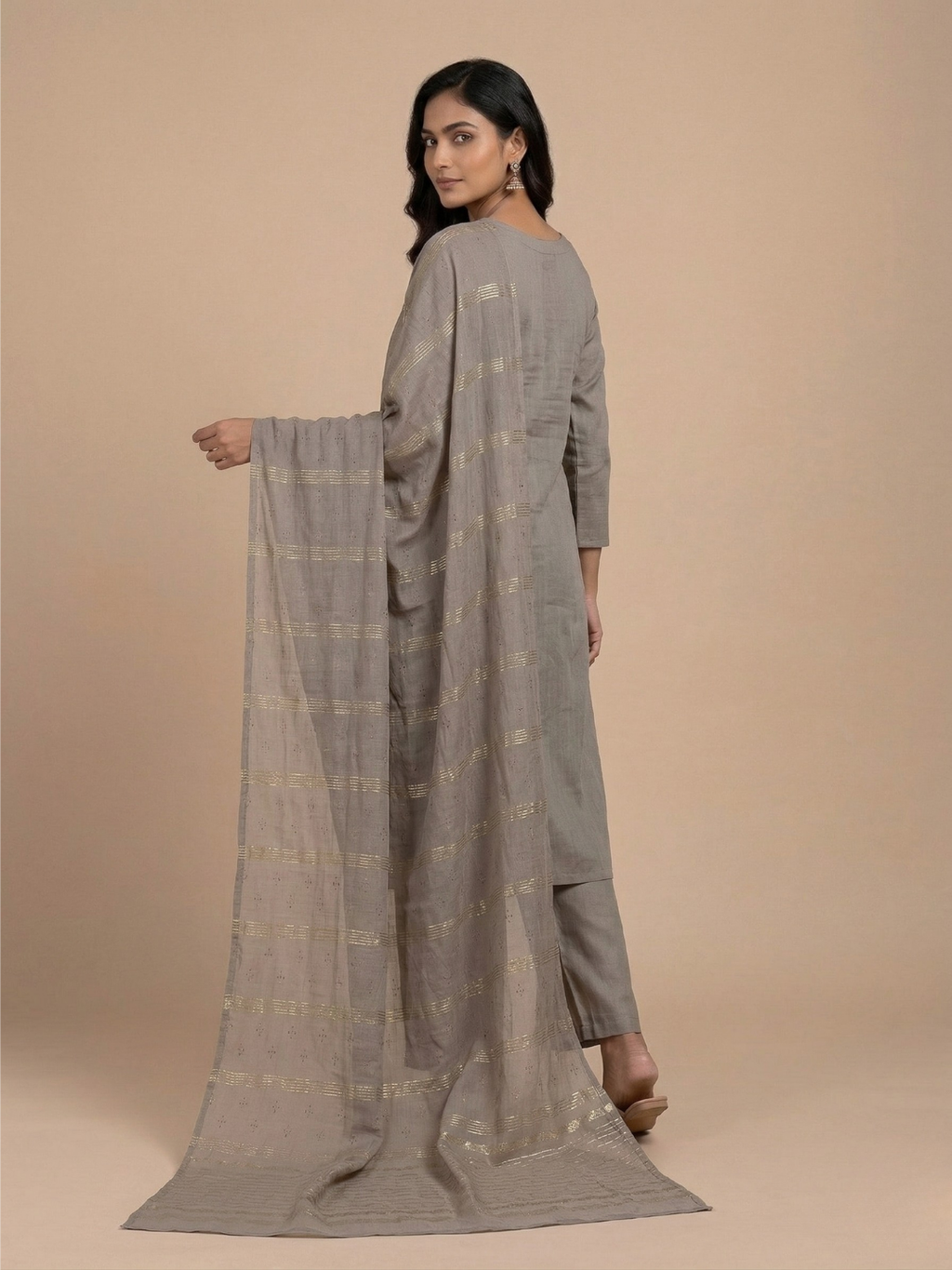 Woman holding a long, patterned scarf against a beige background