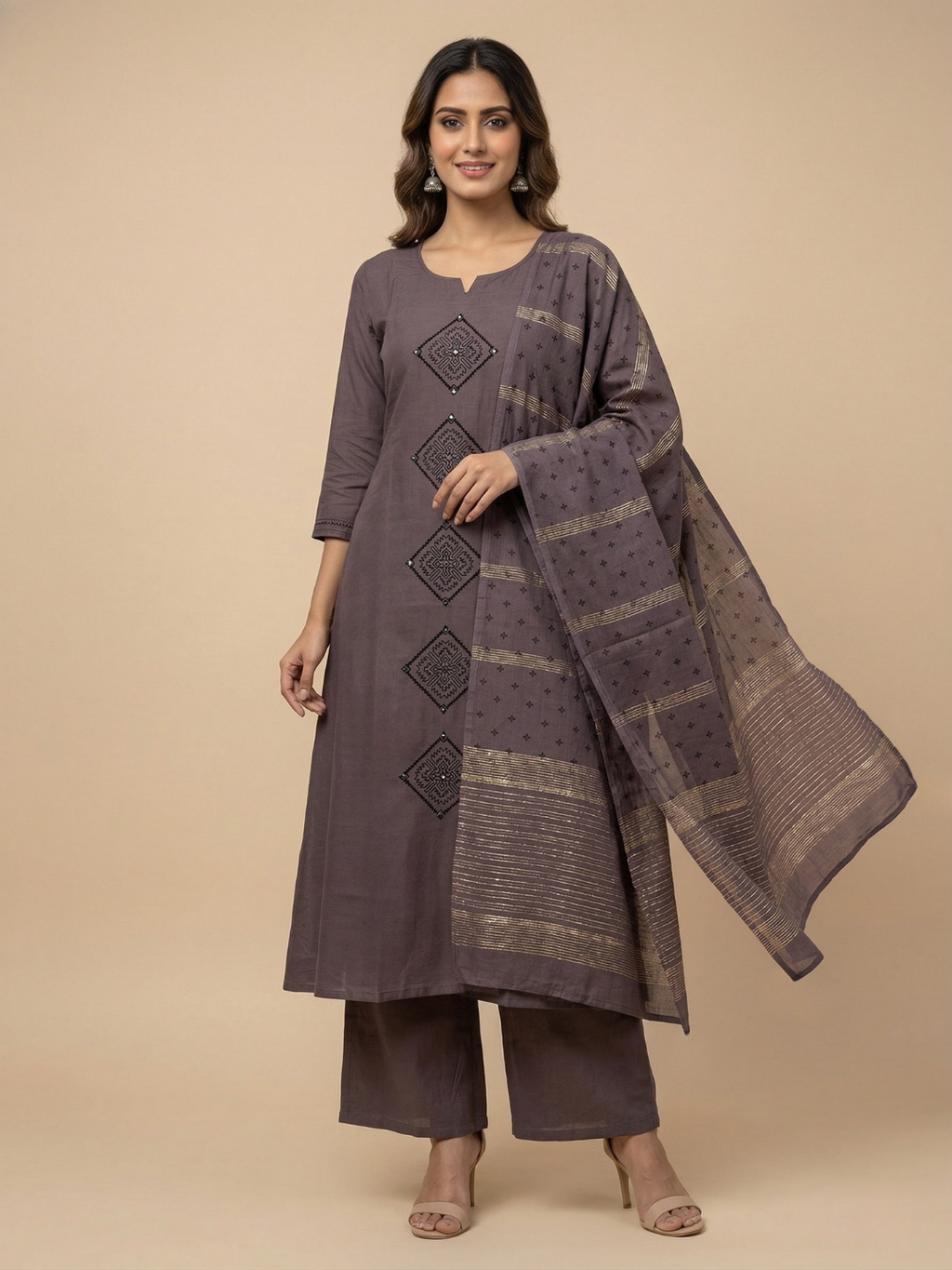 Woman wearing a gray traditional outfit with a matching dupatta on a beige background