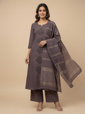 Woman wearing a gray traditional outfit with a matching dupatta on a beige background