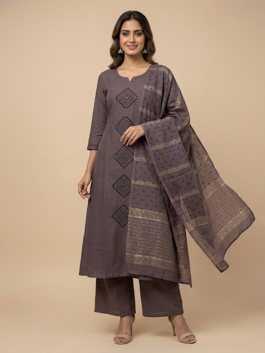 Woman wearing a gray traditional outfit with a matching dupatta on a beige background