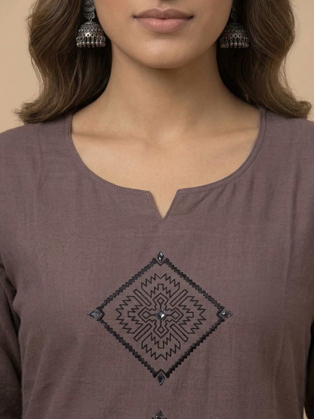 Close-up of a brown top with black geometric pattern and a woman wearing earrings.